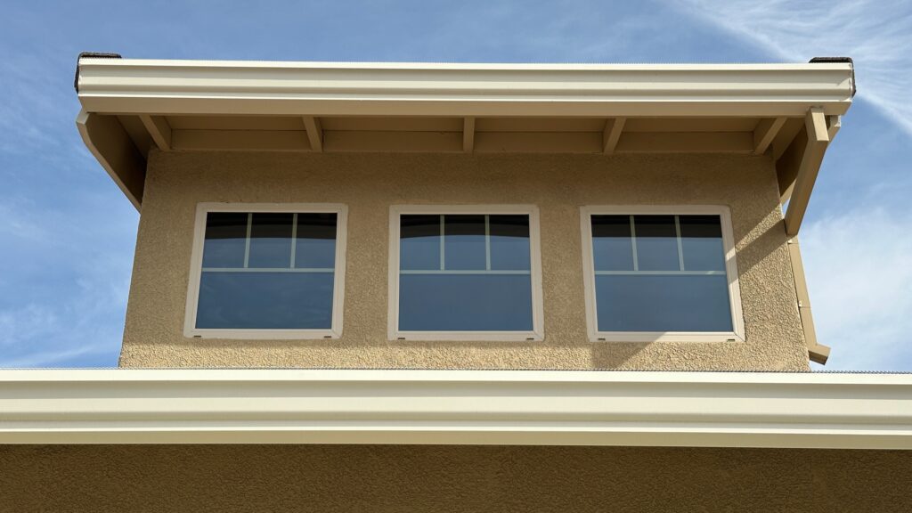 Residential house exterior in El Dorado Hills, showcasing three windows under a roofline with professional-grade paint and durable materials.